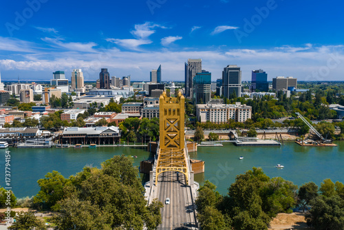 Aerial view of Sacramento, California, featuring the golden Tower Bridge over the Sacramento River, city skyline, and State Capitol Building.