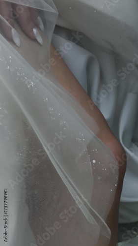 Filling the car image showing a woman's legs and a dress, also known as filling the car. White elegant fabric of dress shines in light. Photo of filling the car shows details like the shiny sparkles.