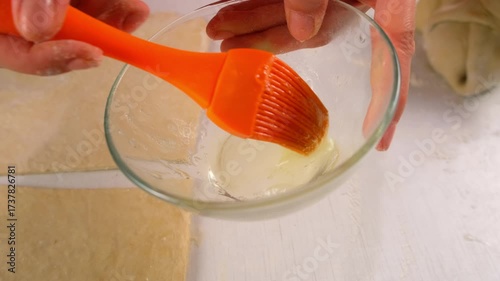 Baker woman hands smearing dough silicone brush with egg white cooking dessert. Create delicious healthy food pastry. Cuisine culinary prepare homemade cook domestic meal baking recipe ingredients.