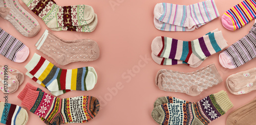 A panoramic background of multicolored socks. The colorful socks are scattered on a pink background. There is space for text.