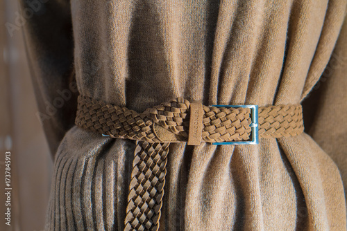A beige belt is tied on a beige wool sweater.