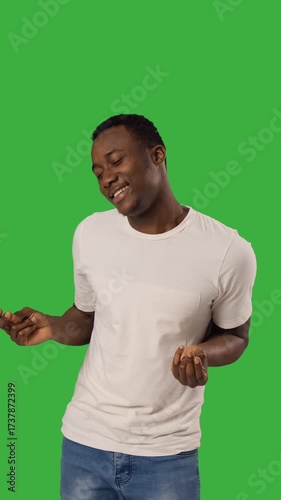 Happy african american man dances over green backdrop.