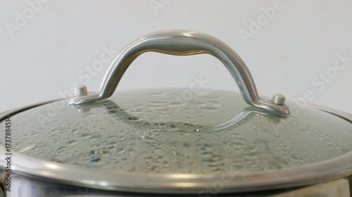 Steam rises as the lid is opened from a stainless steel pot of boiling water. High quality 4k footage