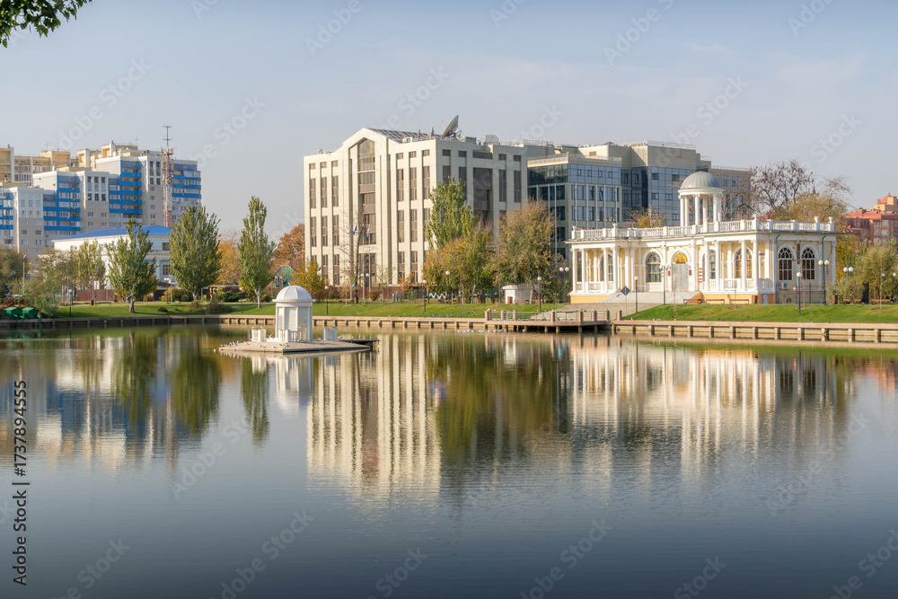 Obraz premium Swan Lake with central gazebo, Astrakhan, Russia, near Lukoil office and planetarium pavilion, calm water, autumn morning and urban park.