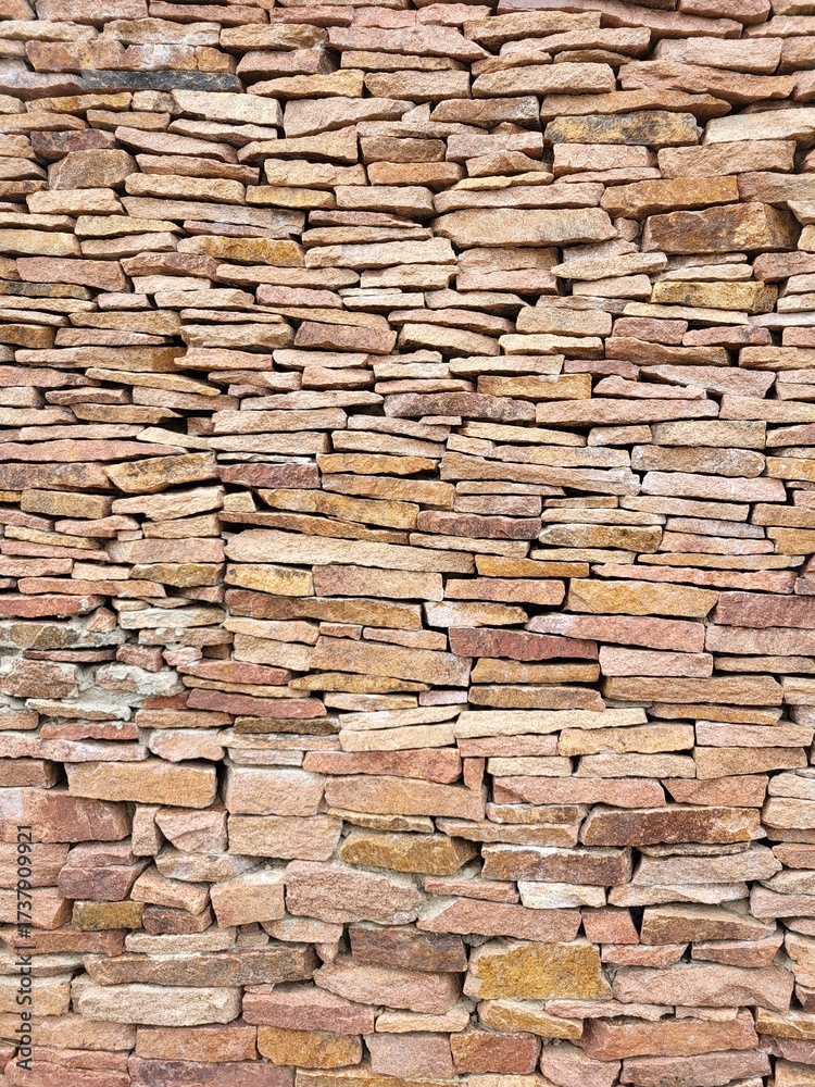 Fototapeta premium Textured sandstone wall. Stacked stones of various shapes and sizes create a strong decorative background in natural warm tones.