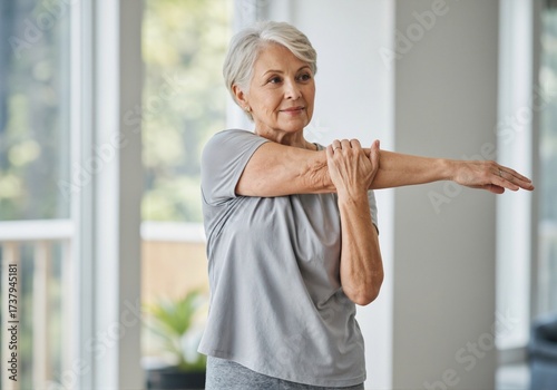 An elderly woman stretching her arms in a gym