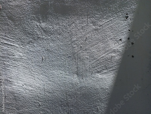 Textured Concrete Wall with Light and Shadow. Close-up of a rough concrete wall surface with natural light and shadow creating abstract texture and depth