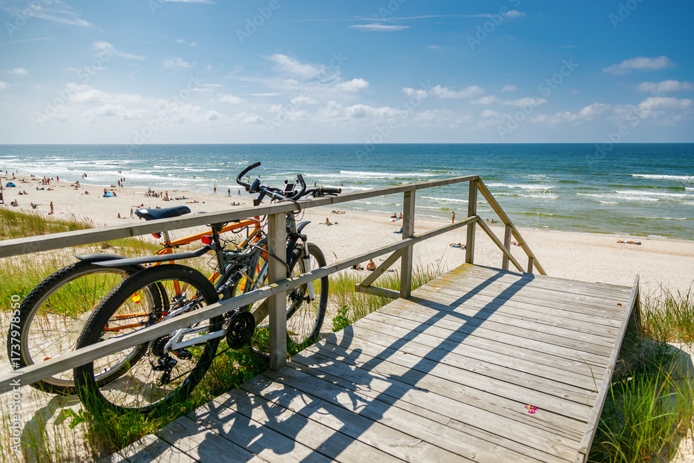 Fototapeta premium Two bicycles parked on a wooden platform above the wide Curonian spit beach and Baltic sea