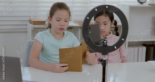 A girl blogger recording phone reading book audio story video blog at home influencer child kid use mobile smartphone camera tripod read study bestseller novel podcast online blogging 4k video.