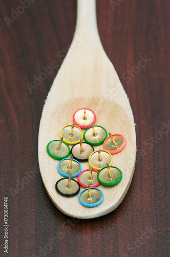 a wooden spoon with drawing pins