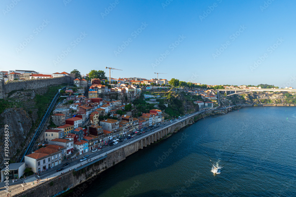 Obraz premium Scenic view of colorful hillside houses and riverside promenade along the Douro River in Vila Nova de Gaia, Porto, Portugal.