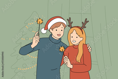 A joyful festive couple happily celebrating the Christmas holiday while holding sparklers