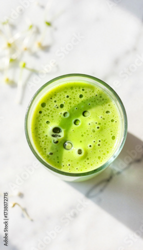 Green smoothie in glass on marble surface with fresh ingredients  
