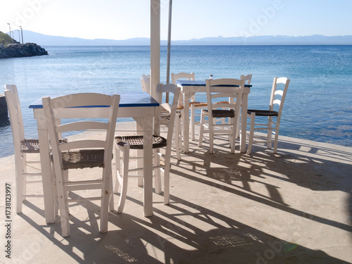 Kitries village, Mani Peninsula - Greece - September 21 2025 - Greek seaside taverna. View of the terrace with shadows cast by the late afternoon sun. Tables and chairs.
