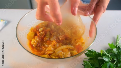 Woman chef hands pressing vegetables stew in bowl using glass cooking on kitchen. Culinary techniques, homemade preparing healthy meal cook food dish, cuisine, seasoning garlic parsley greenery.
