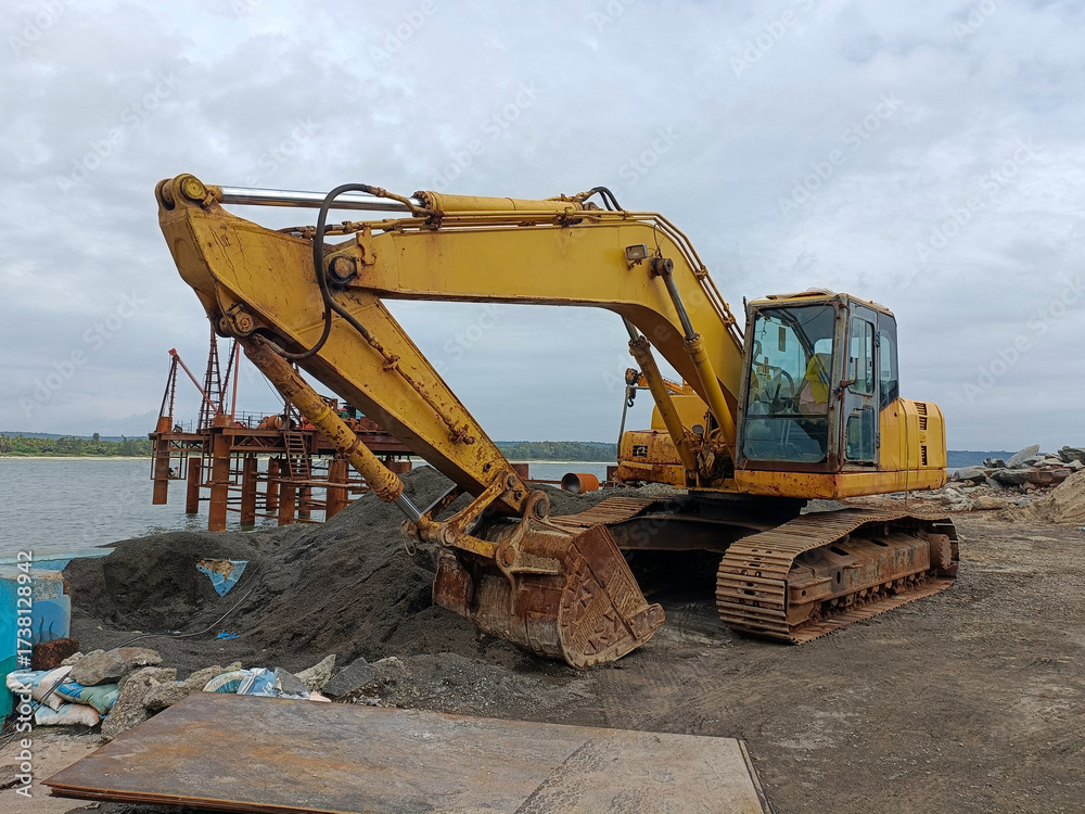 Fototapeta premium Yellow Hydraulic Excavator Parked at a Coastal Construction Site