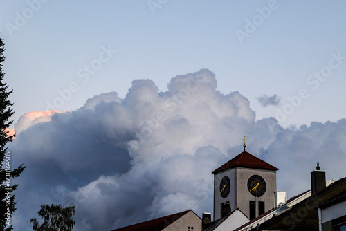 Threatening dark storm clouds with a bright pink tip over the church of St Albert in Augsburg Haunstetten