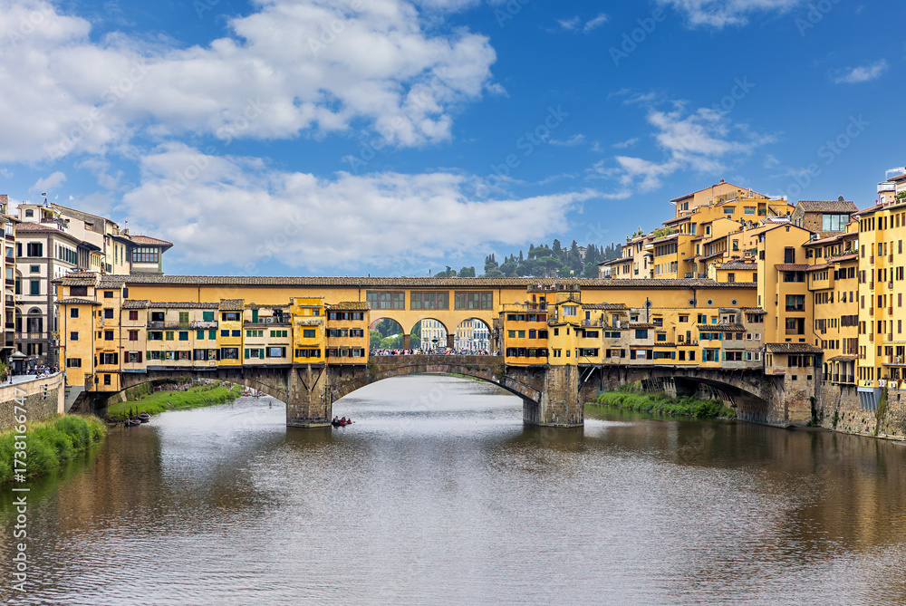 Obraz premium Ponte Vecchio bridge stands over the Arno River in Florence, surrounded by historic buildings.
