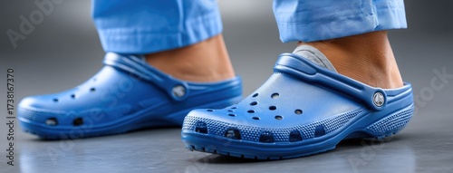Health care professional wearing blue scrubs and footwear in a hospital environment during a busy morning shift
