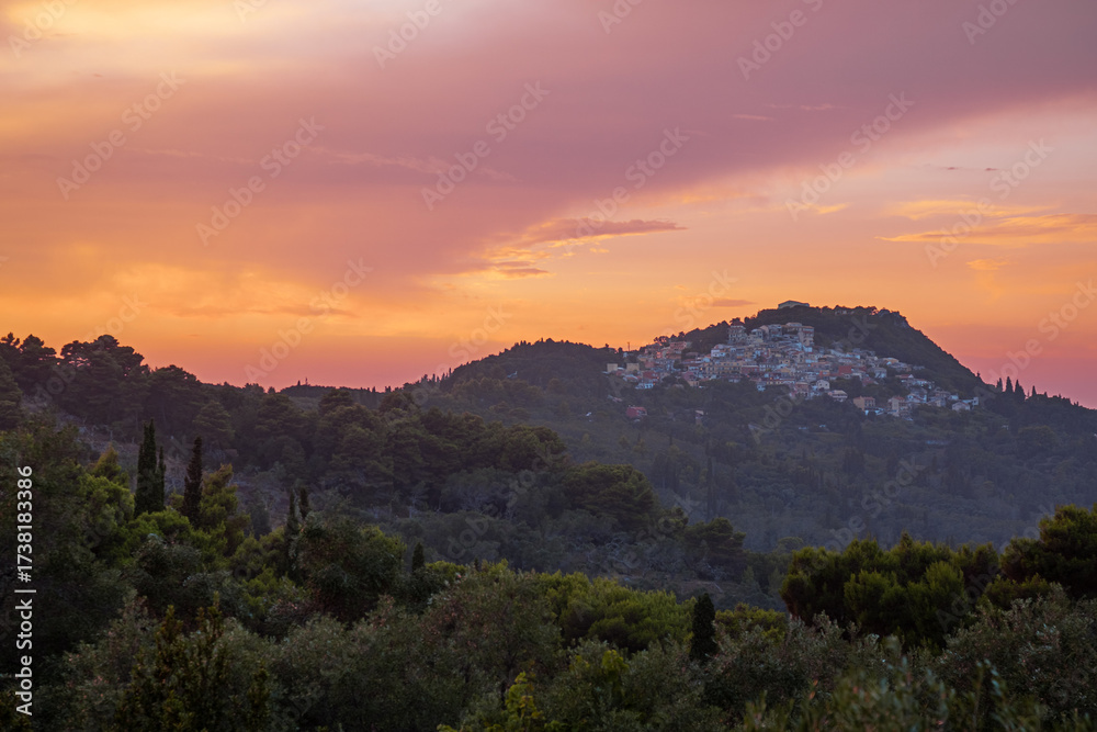 Obraz premium Landscape with a distant greek village on the hill at sunset. Pelekas village, Corfu, Greece