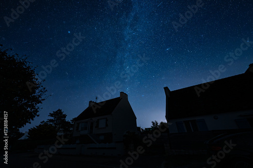 A few house silhouettes against a starry night sky with the Milky Way.
