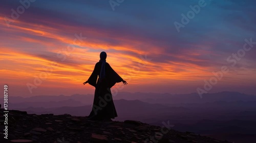 Silhouette of a woman at sunrise over a mountain range