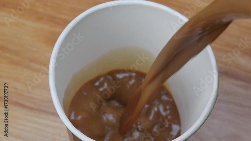 4K footage Pouring Iced Coffee into white paper Cup.