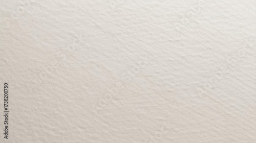 Textured beige paper showcases its rough and grainy surface, creating a subtle pattern of shadows and highlights on a neutral s sheet.
