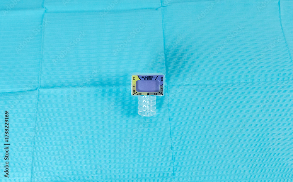 Fototapeta premium Medical capnography adapter used for connection to an Ambu bag for patient CO₂ monitoring, placed on a sterile blue background.