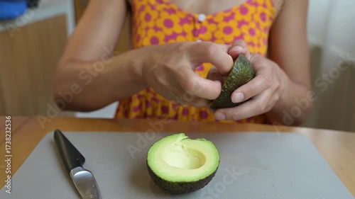 Close-up video of a person cutting a fresh avocado in half, showing the seed and pulp on a kitchen cutting board during meal preparation