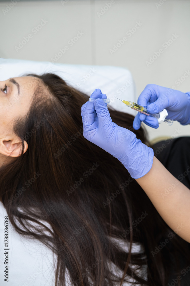 Fototapeta premium Caucasian female mature patient getting head or scalp injection in cosmetology clinic. Receding hairline, baldness problems, hairloss. Cosmetologist doing injections with syringe. 