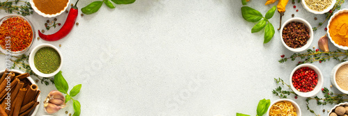 A wide selection of cooking spices and herbs on a gray background, perfect for adding depth to any dish, top view and copy space, banner