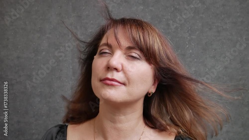 Beautiful woman 40-50 years old close-up serious, wind blowing hair
