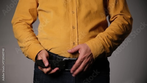 Middle-aged man unbuckles and refastens his belt