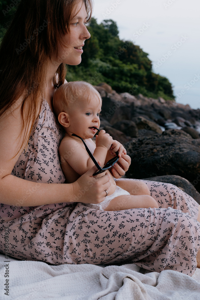 Φωτογραφία Caucasian female adult with baby outdoors near rocky shoreline on cloudy day