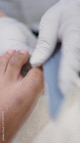 Professional pedicurist filing man's toenails during pedicure treatment