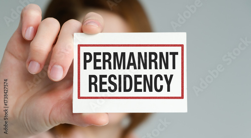 A person is holding a card that says Permanent Residency
