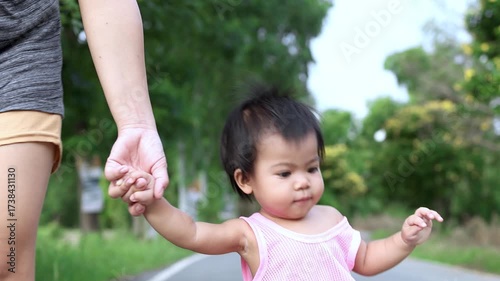 cute little baby walking while holding an adult hand outdoors, mother and baby playing happily, happy mom and baby activities, symbolizing love, care, and family bond
