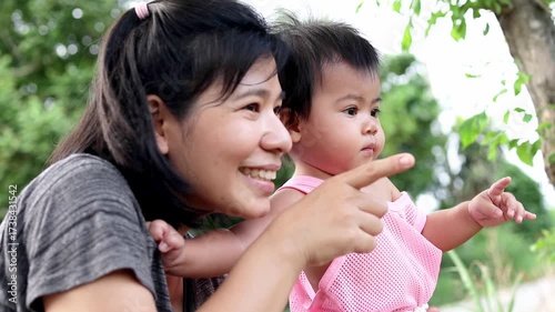Mother holding baby and pointing with a smile, showing love, warmth, and joyful family moments