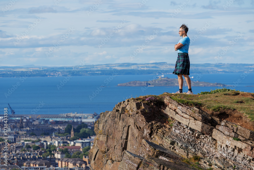 Fototapeta premium Man in kilt gazes at the ocean from a rocky cliff edge, Scotland