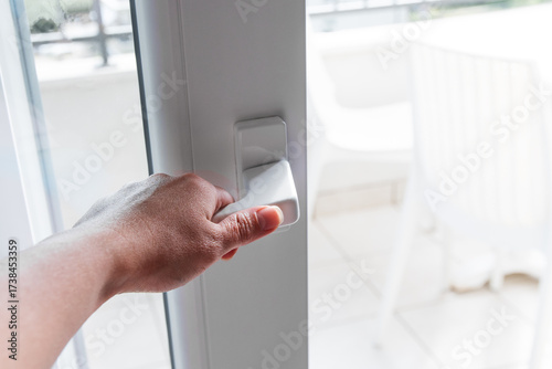 Close-up of a woman's hand holding a door handle to open the balcony door.