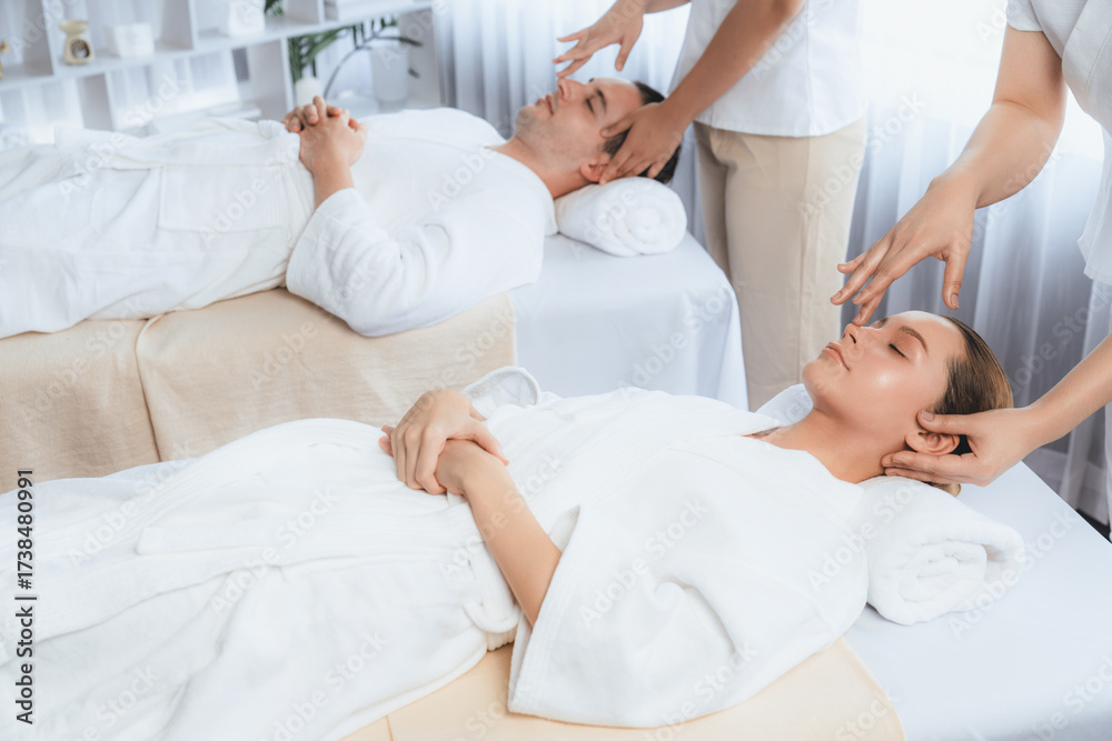 Obraz premium Caucasian couple enjoying relaxing anti-stress head massage and pampering facial beauty skin recreation leisure in dayspa modern light ambient at luxury resort or hotel spa salon. Quiescent