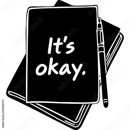 Black notebook with “It’s okay” written on cover and pen nearby  