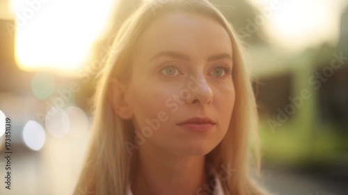 Smiling blonde woman outdoors at sunset, looking happy and confident with warm golden light creating soft bokeh background