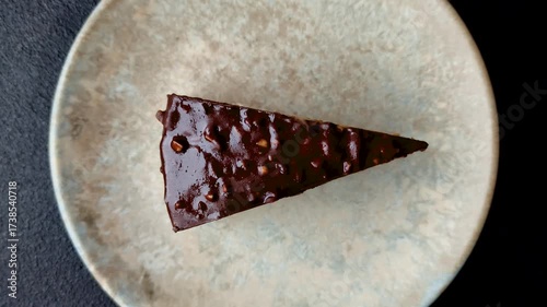 A slice of sweet layered cake covered in chocolate with nuts and caramel. A slice of chocolate cake