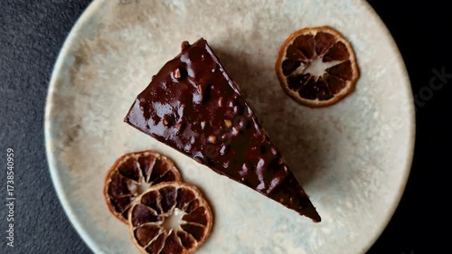 A slice of sweet layered cake covered in chocolate with nuts and caramel. A slice of chocolate cake
