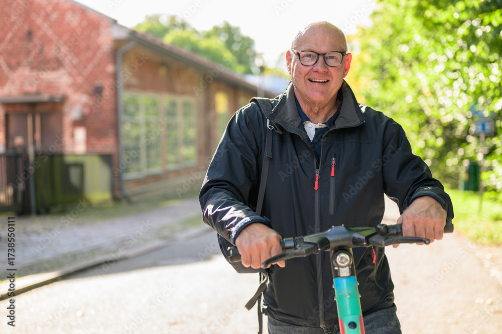 Obraz premium Portrait of a smiling senior man riding a electric kick scooter in city