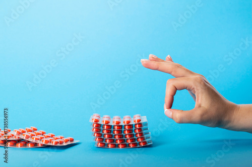 Wallpaper Mural Female hand flicking a stack of pills on a blue background. Concept of treatment with chondroprotectors. Copy space for text Torontodigital.ca