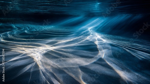 A mesmerizing underwater background with beams of light filtering through the clear blue water. The light creates a dynamic ripple effect on the ocean floor