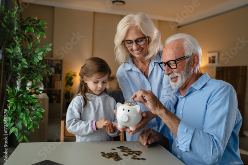 Foto Grandparents teaching granddaughter financial literacy with piggy bank
